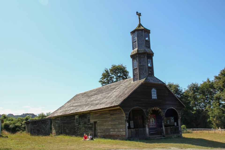 Weathered timber Church of Colo with a shingled tower and broad pitched roof in rural Chiloé