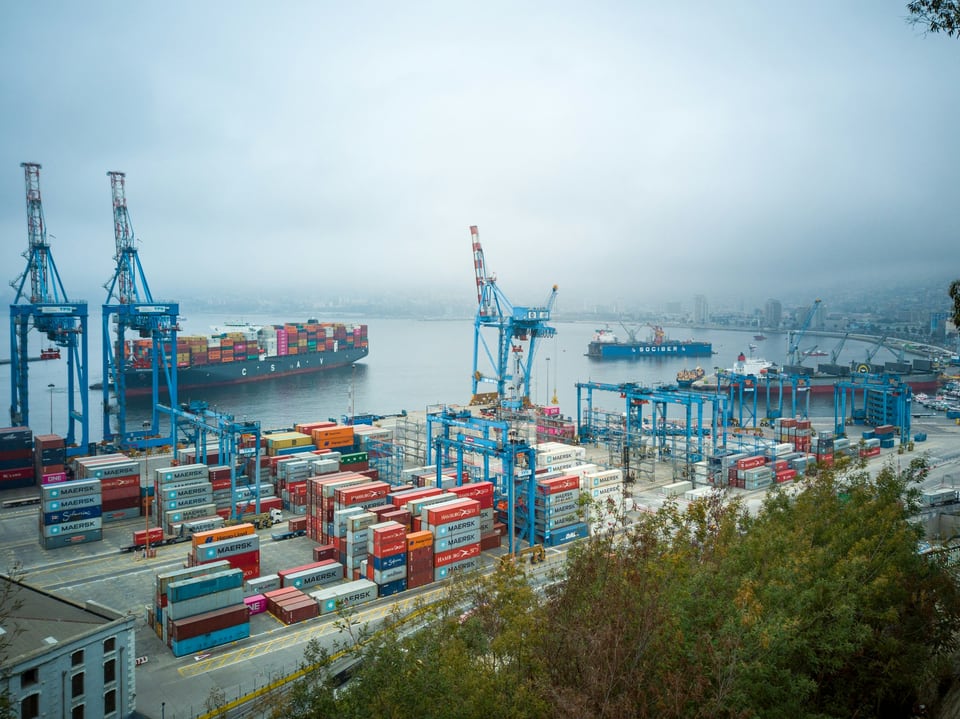 Container stacks, gantry cranes and cargo ships across the working port of Valparaíso in coastal mist